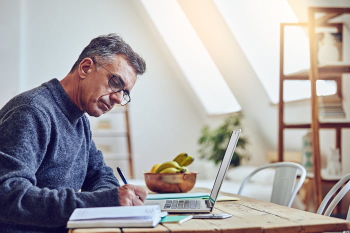 A person at a laptop taking notes.