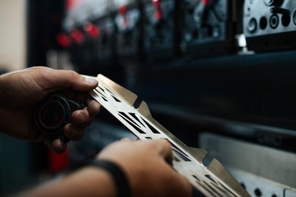 A person looks at a cut metal part.