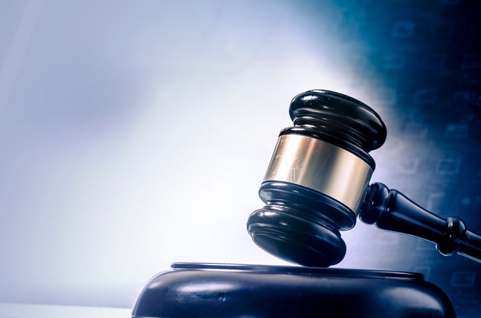 A judge's gavel resting on a wooden block with faint digital data in the background.