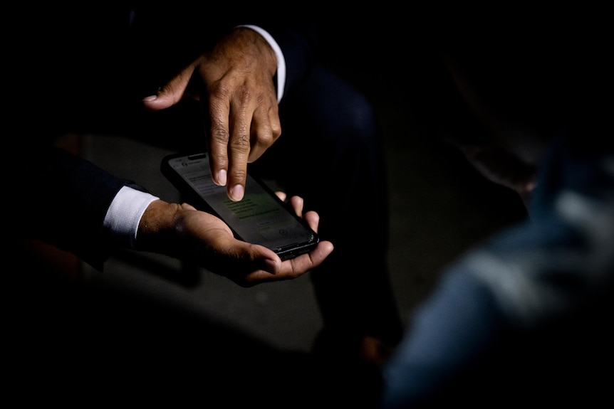 A hand scrolling through messages on a phone screen.