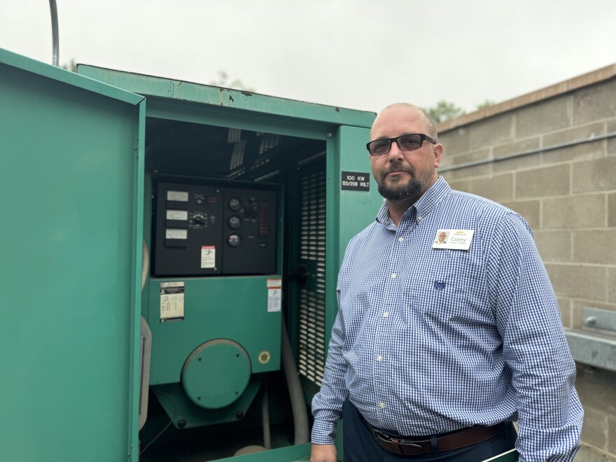 Corey Dragge poses in front of a green backup generator outside Frasier.