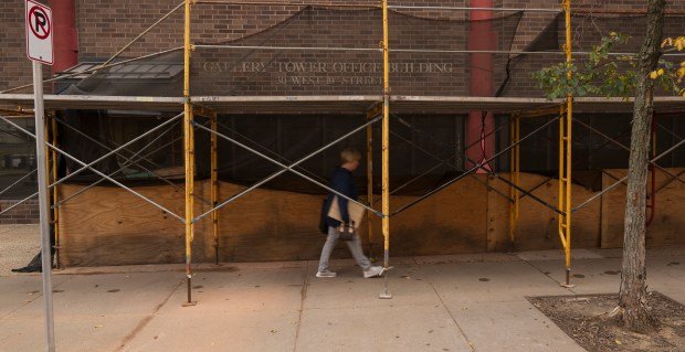 A pedestrian walks under scaffolding