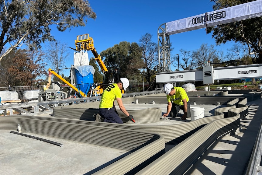 two men working on a construction site using a 3d printer