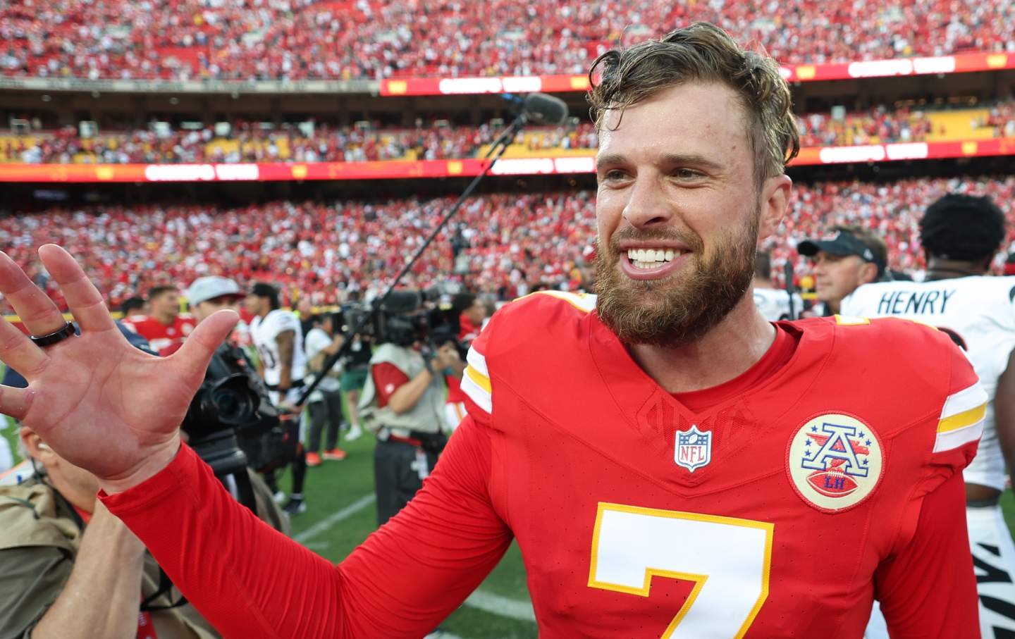 Harrison Butker smiles and reaches his hand out to greet someone off camera.